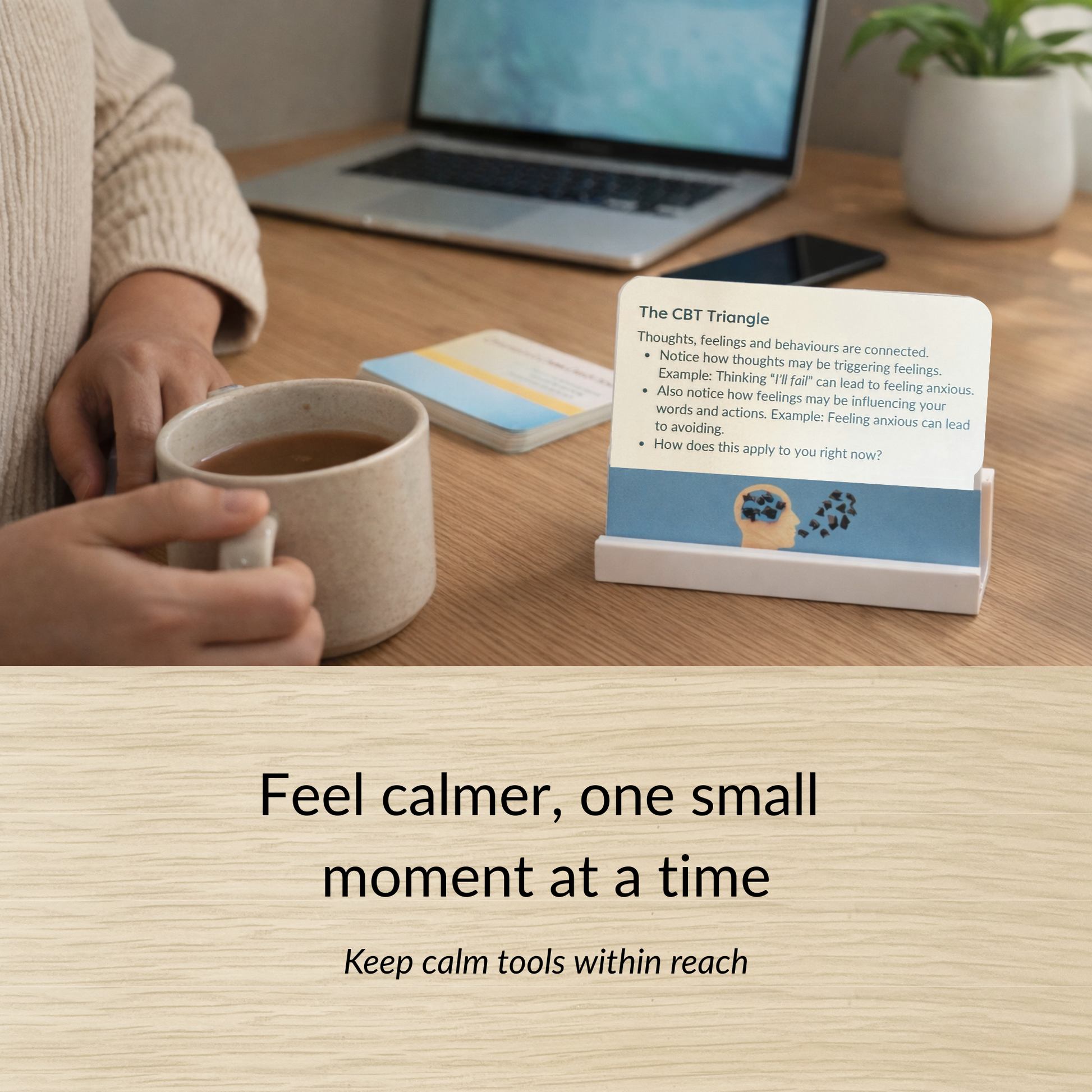Calm Cards display stand on a desk beside a cup of tea and laptop showing how the card deck can be kept visible for daily emotional support